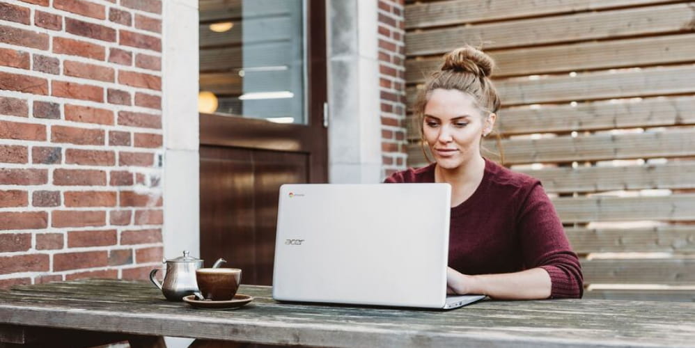 Woman using laptop outdoors at a café, researching what an IBAN is for international bank transfers.
